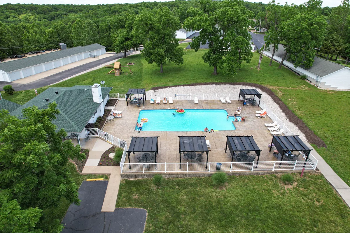 A large pool area featuring cabana structures, poolside loungers, and abundant greenery. The setting feels private yet social, with ample space for relaxation and group activities. The mood exudes leisure and fun, aligning with the idea of shared moments by the pool.