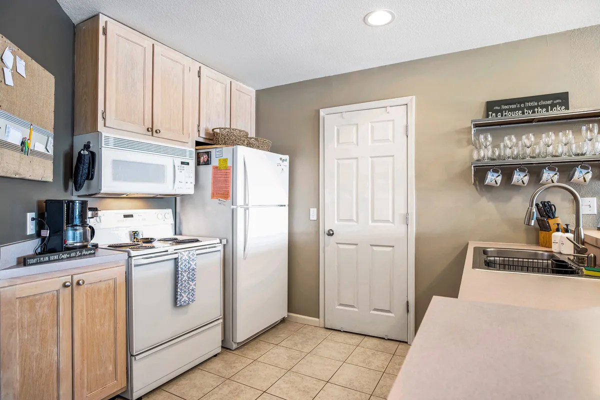 A bright, well-equipped kitchen with modern appliances, abundant cabinets, and a generous countertop, all complemented by homey décor. The space is inviting for meal prep, group cooking, and casual gatherings around the kitchen.