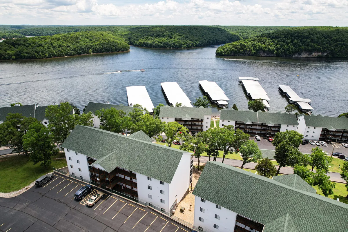 An inviting exterior shot captures the lake, boat docks, and nearby residential buildings surrounded by trees and greenery. The calm mood is underscored by the gentle sunset glow, and the docks provide a launching point for boating or nature walks.