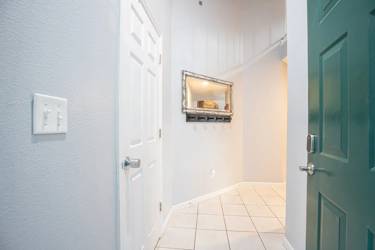 A welcoming entryway with a green front door, a decorative mirror, and tile flooring creates an inviting first impression. The space is neat and stylish, suggesting security and a sense of arrival.